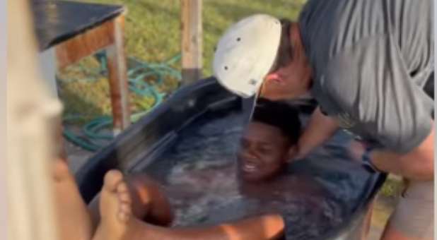 Coach Isaac Ferrelll baptizes one of his football players.