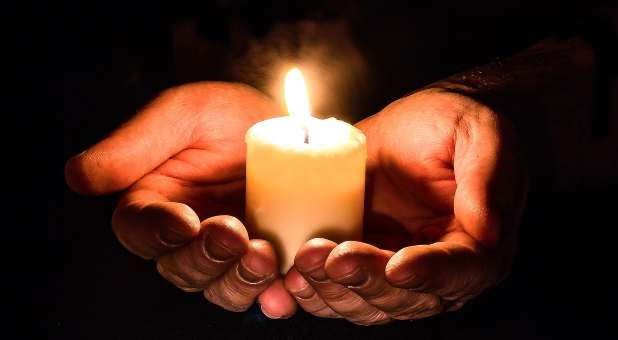 hands cupped around candle