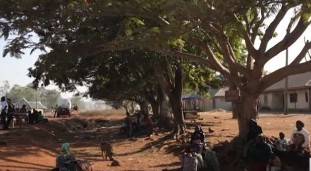 Nigerian villagers under trees, outside homes in affected Nigerian village