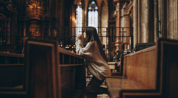 A young woman praying in a cathedral.