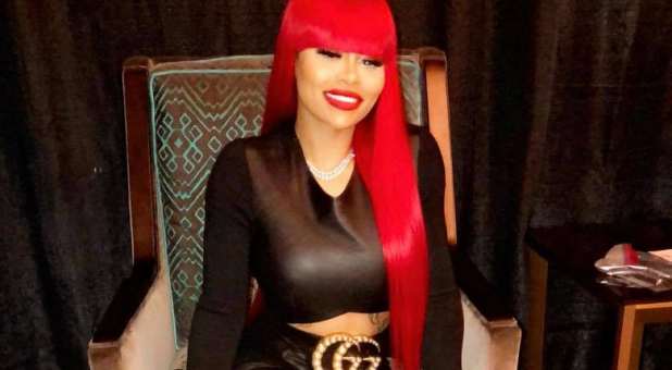 Celebrity Blac Chyna with long red wig, seated in chair