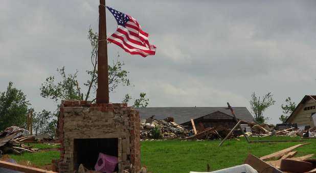 destroyed home with torn American flag flying overhead