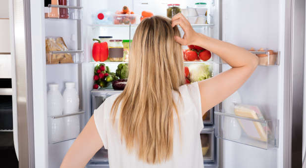 A woman looking for food in a refrigerator.