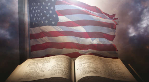 American flag waving behind large Bible.