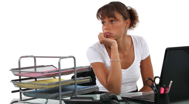 A woman in a bad mood sitting at a work desk.
