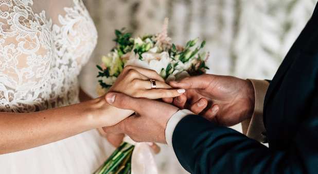 Wedding scene showing bride and groom's hands with wedding ring