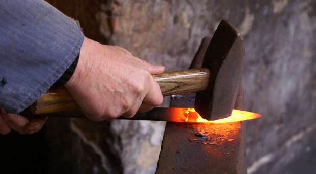 Blacksmith using hammer to forge iron.