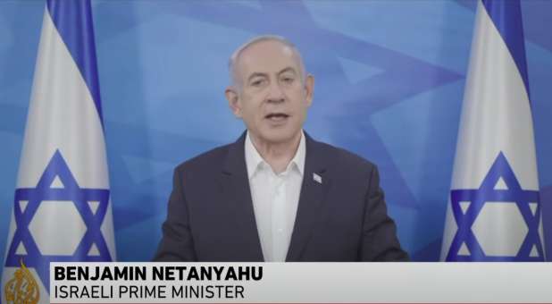 Netanyahu speaking, a flag of Israel on each side.