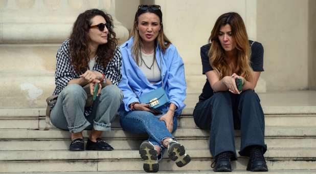 Three young women sitting on steps and talking.